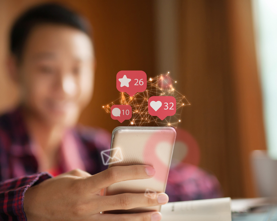 Person hält ein Smartphone, darüber schweben Social-Media-Benachrichtigungen mit Likes, Kommentaren und Favoriten – symbolisiert Reichweite, Engagement und digitale Interaktion im Social-Media-Marketing.
